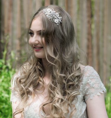 Bridal headpiece with ivory enamel flowers and blush beaded flower on a bride with long hair