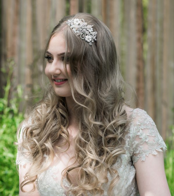 Bridal headpiece with ivory enamel flowers and blush beaded flower on a bride with long hair